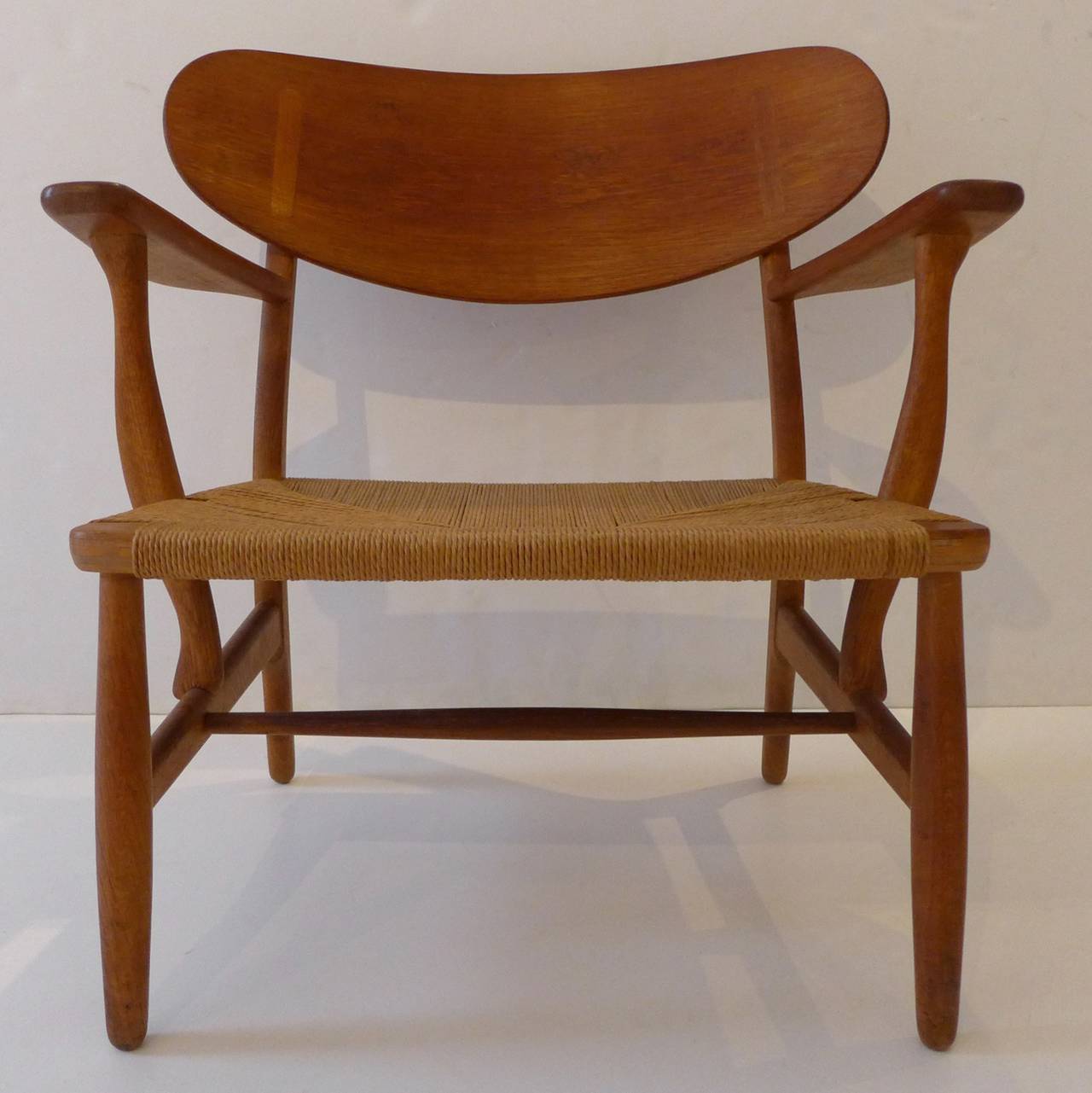VIntage CH-22 lounge chair in stained oak with a laminated oak and woven paper cord seat. Designed by Hans Wegner in 1951 and produced by Carl Hansen c. 1950's.  A classic combination of sculptural beauty and comfort by one of Denmark's (and,