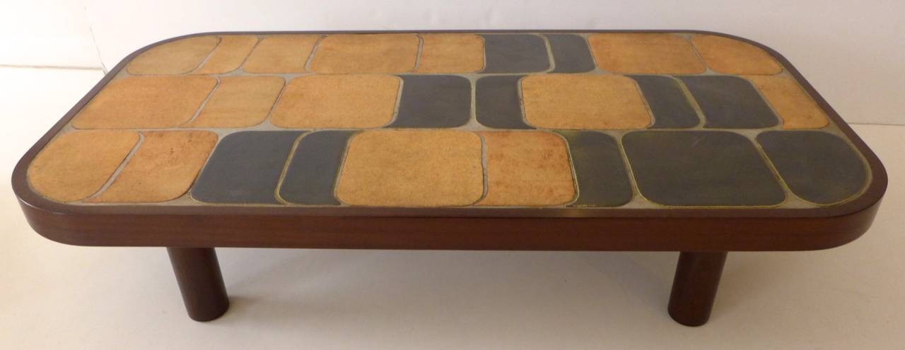 Large cocktail table consisting of ceramic tiles set into a wooden frame by French ceramic artist Roger Capron, executed early 1970s. A pleasing abstract pattern in a nicely modulated color scheme. The dark-stained frame has softly rounded edges and
