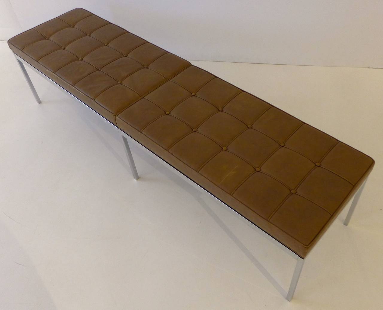 Six foot long bench of chrome-plated steel and leather, designed by Florence Knoll and produced by Knoll, circa 1970. Upholstered in individual welted panels with button tufting. In fine vintage condition, with some minor wear and scuffing to the