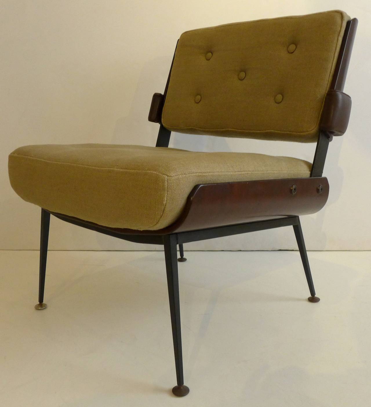 Sleek and stylish pair of lounge chairs with attenuated wraparound arms by French designer Alain Richard, circa 1960. The seat and back shells are laminated mahogany; the base is enameled steel. The arms are wrapped in leather, as is the steel