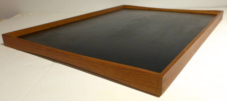 Double-sided serving tray of teak and melamine, designed by Finn Juhl and produced by Torben Orskov, circa 1958.  The gently curving end pieces provide a finger grip and add visual flair, as does the contrasting laminate colors--black on one side,
