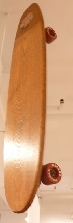 Vintage skateboard of solid oak with hard rubber wheels and rubber shock mounts by Hawaiin firm Makaha International, which also made surfboards.  A sleek piece of 