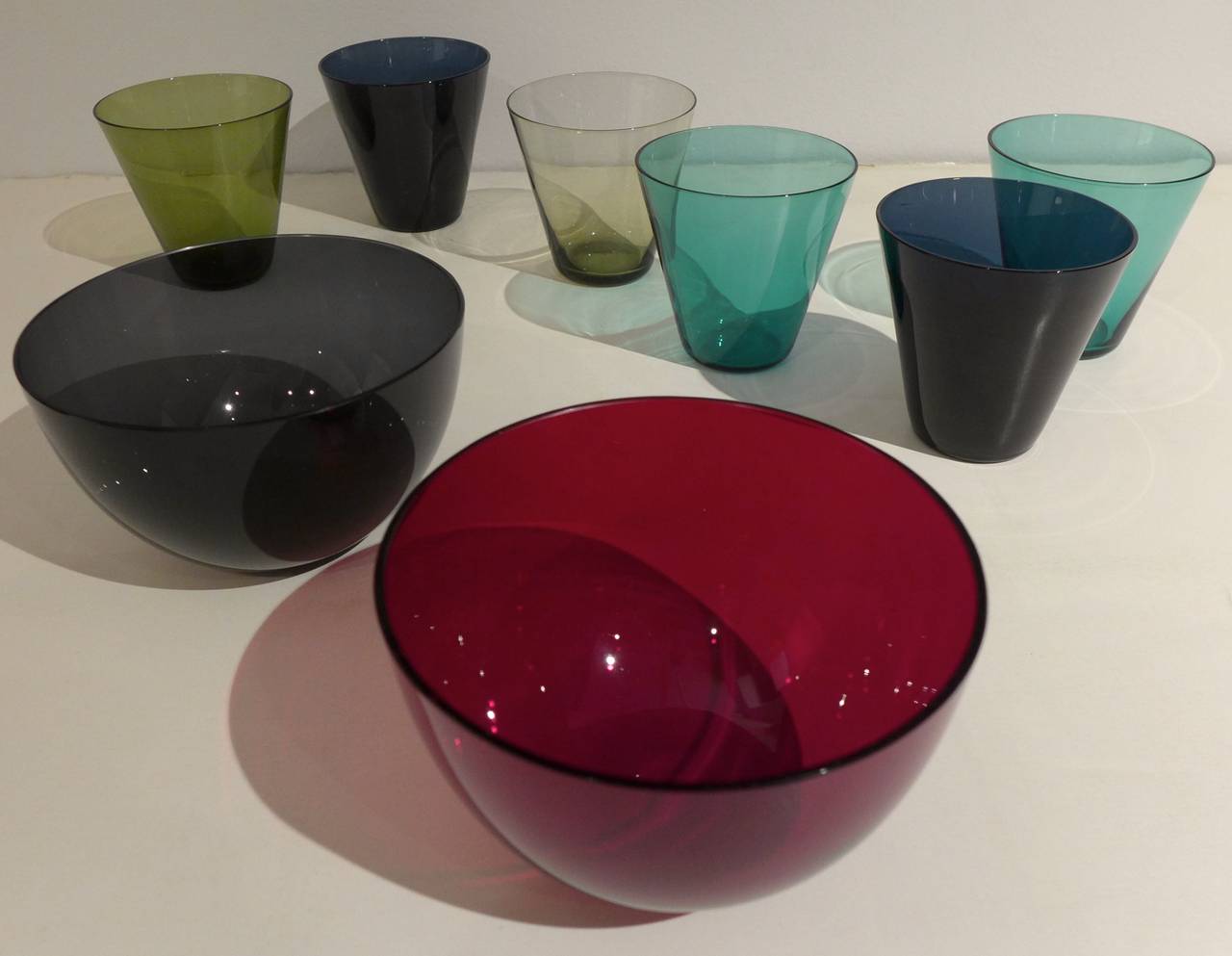 Set of blown glass vessels from the 2744 series, designed by Kaj Franck and produced by Nuutajarvi Nottsjo, Finland, from 1955-67.  Comprising six glasses and two bowls in deep blue, green, red, pale blue, and smoked glass.  Widely acclaimed in its