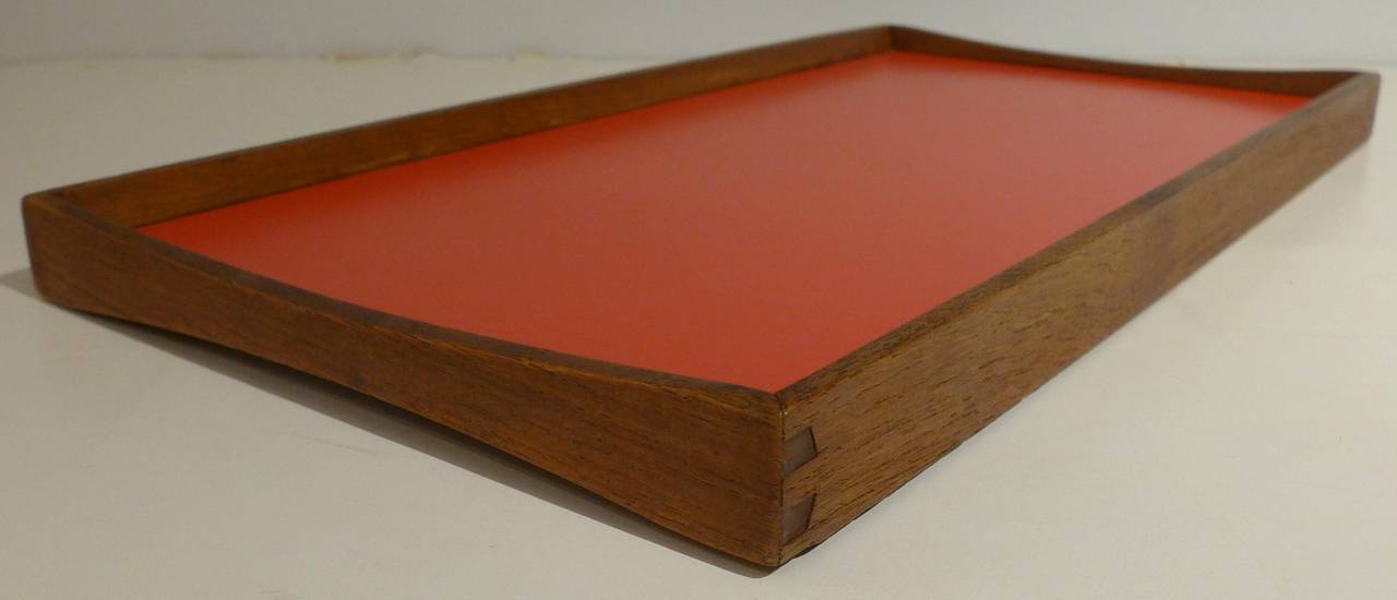 Double-sided serving tray of teak and melamine, designed by Finn Juhl and produced by Torben Orskov, circa 1958. The gently curving end pieces provide a finger grip and visual flair, as does the contrasting laminate colors--red on one side, black on