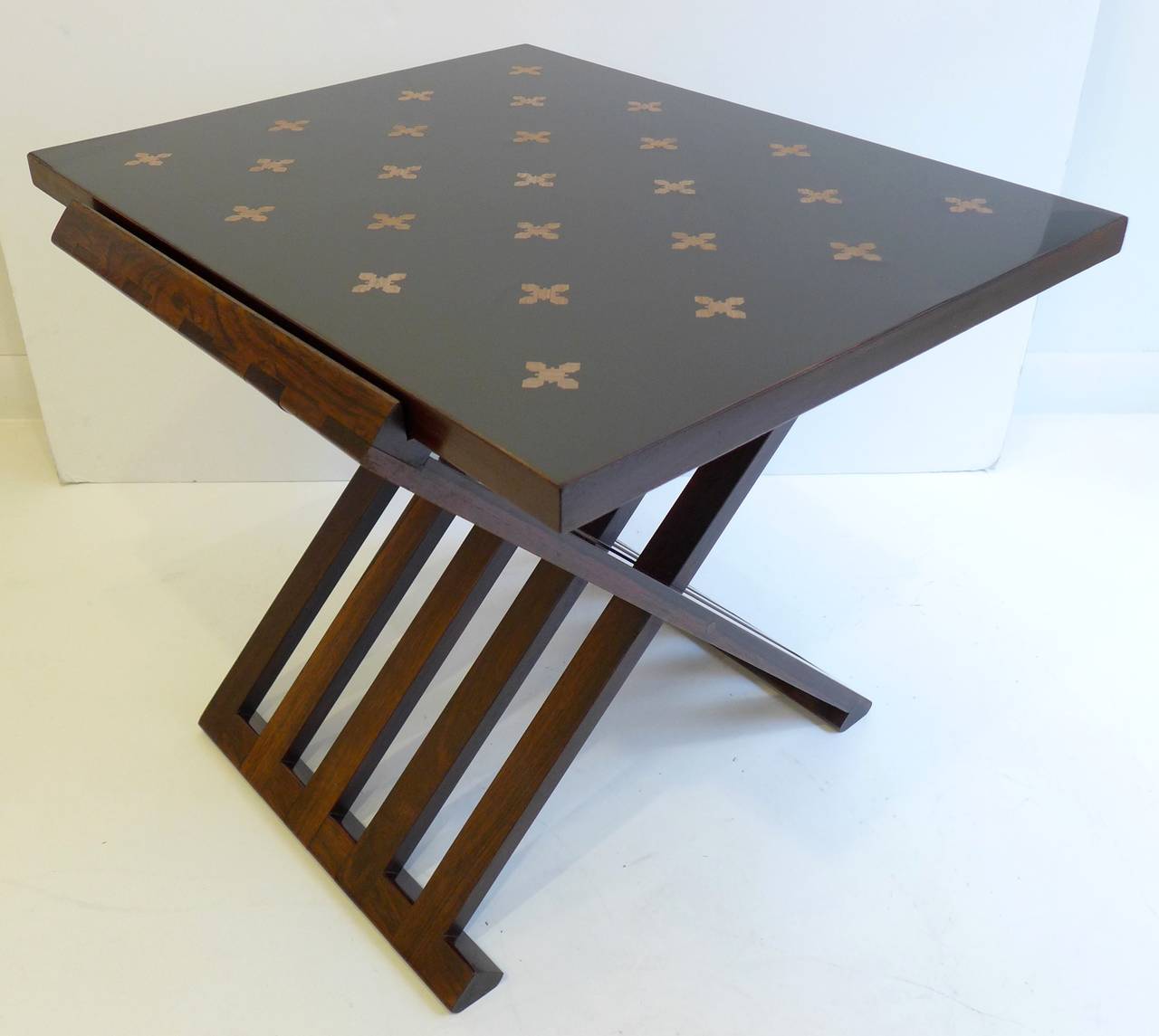 Parquetry occasional table, model 5425, designed by Edward Wormley and produced by Dunbar Furniture, circa 1956. The folding rosewood base holds the mahogany-edged top with bleached mahogany parquetry inset into black micarta. Retains the gold