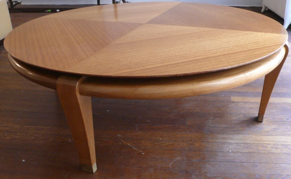 Coffee table with floating round top and pie-shaped patterning in bleached mahogany, and four carved legs with brass sabots.  Designed by Paul Laszlo for Brown-Saltman, 1950's.