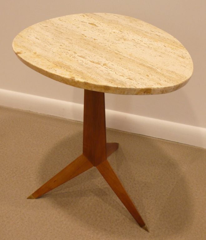 Cocktail table with lozenge-shaped travertine marble top and tripod walnut base with brass sabots.  Stylish and unusual, Italianate piece by Widdicomb Furniture, dated 1957.  Refurbished.