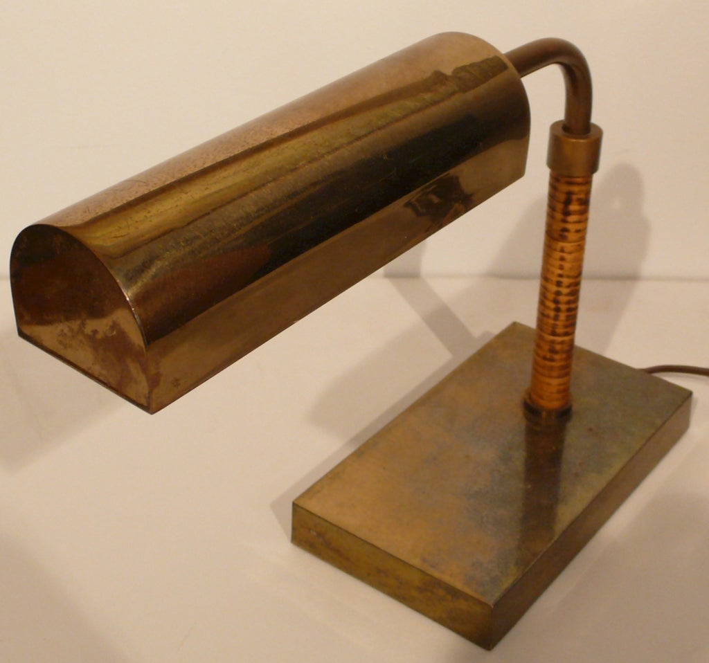 Laterally adjustable (pivots and swivels) desk lamp manufactured by Chapman, c. 1976.  Small but nice form; also nice mix of materials--brass plated metal with caning, sort of Paavo Tynell meets Peter Pfisterer.  Patina and wear to the metal,