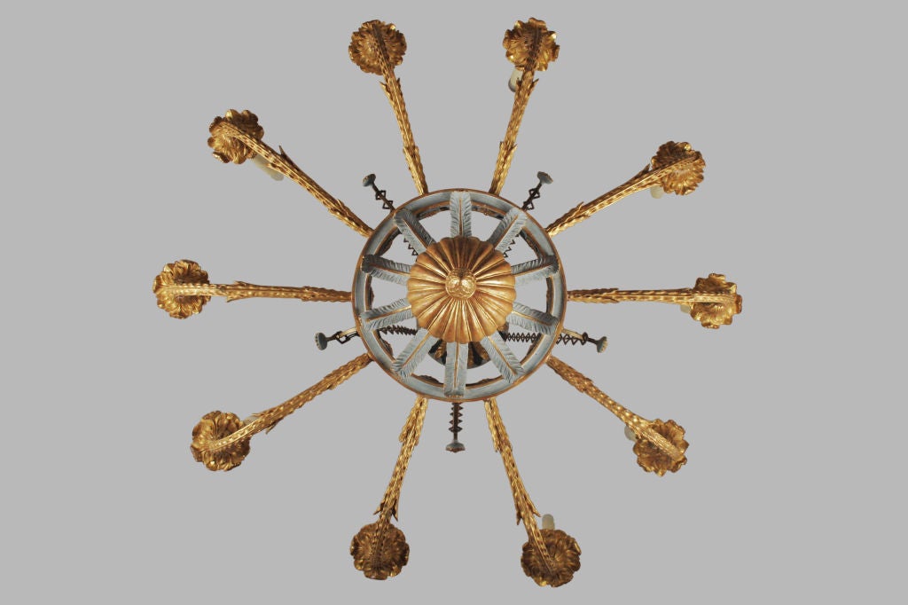 The gilt, ebonized and blue painted leaf tipped corona issuing five chains suspending a blue and parcel gilt wheel decorated with leaves and an acorn finial.  The eight upturned gilt foliate arms are electrified.