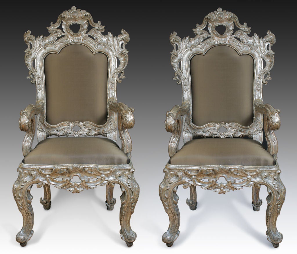 The cartouche shaped back elaborately carved with rocaille and c-scrolls framing an inset upholstered back flanked by similarly carved arms raised on reverse cabriole legs.  The attached seat above a pierced apron raised on cabriole legs and