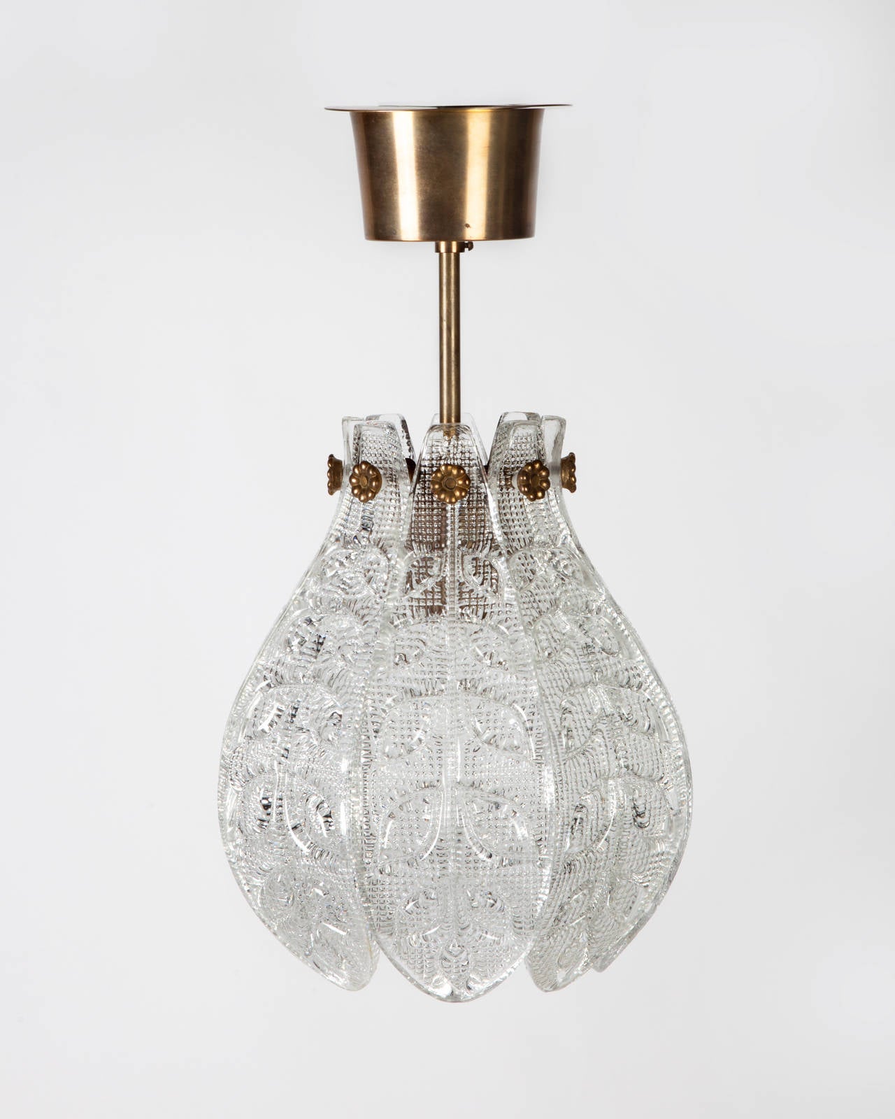 AHL3882

Circa 1950
A vintage, Scandinavian modern, tulip cup shaped pendant with foliate-detailed glass petals on its original aged brass fittings. Designed by Carl Fagerlund for the Swedish glassmaker Orrefors. Due to the antique nature of this