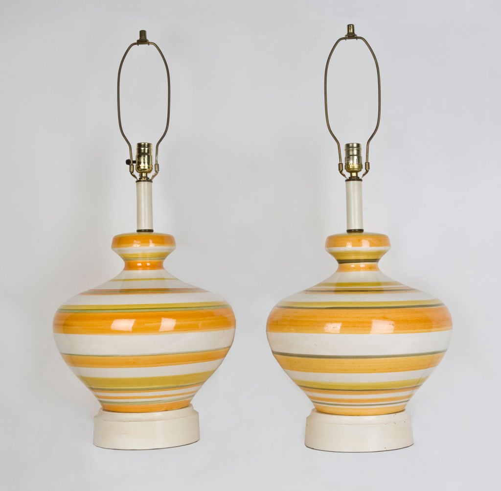 ATL1828
A pair of colorful ceramic stoneware lamps with horizontal stripes in orange, yellow, and pale green glazes. Having lacquered and age-darkened brass fittings. Due to the antique nature of this item there may be imperfections in the glaze and