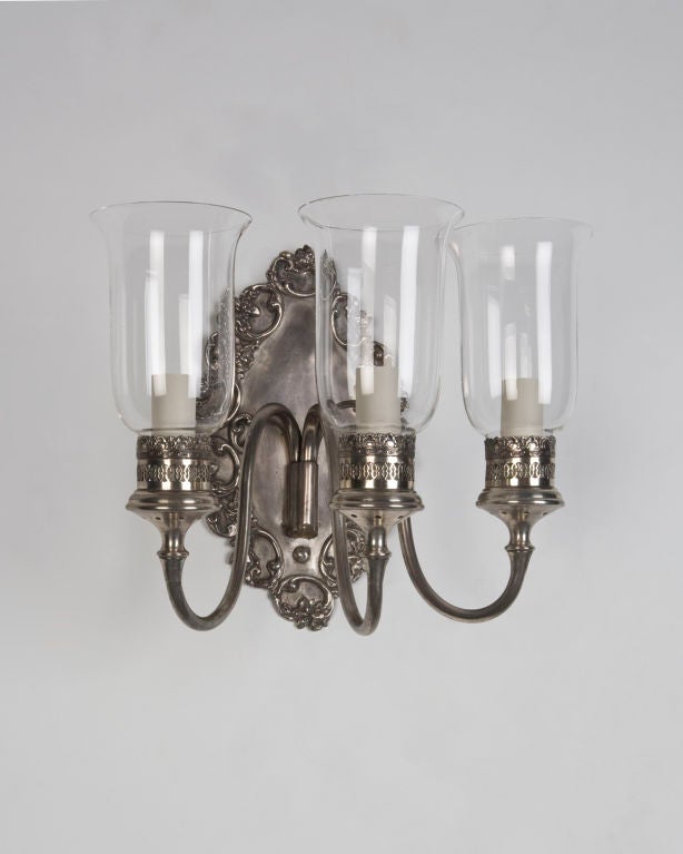 AIS2729

A pair of three-light brass sconces in an aged silver finish with clear glass hurricane shades. Signed by the New York maker E. F. Caldwell.

Overall: 11-1/4