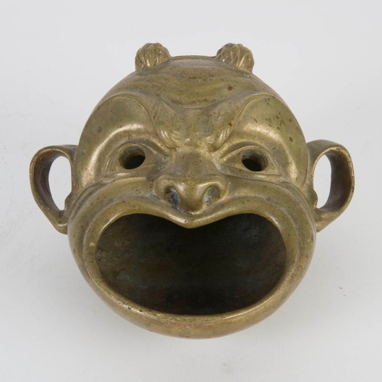 ATA1386<br />
A bronze open-mouthed face coin dish. The design is based on a pompeian lamp from the 1st century A.D. By the New York maker Sterling Bronze Co.<br />
<br />
Overall: 3-1/2