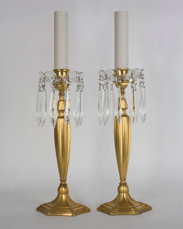 ATL1836
A pair of single light gilt bronze electrified candlesticks having crystal bobeches dressed with spear and rosette prisms. Signed by the New York maker Sterling Bronze Co.

Dimensions:
Overall: 21