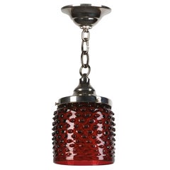 A red hand-blown hobnail patterned glass pendant