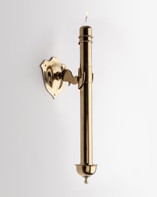 AIS2768

A pair of candle sconces in polished brass. The torch is fitted with a spring mechanism roughly calibrated to the weight of a wax taper, consistently feeding the candle up as is burns. The torch is removable from the bracket arm for