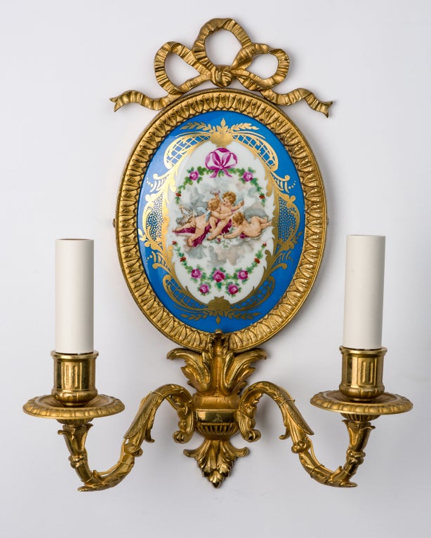 AIS2773

A pair of gilded bronze double-light sconces with hand-glazed ceramic backplates depicting an angelic scene set in bow-topped leaf-and-dart bezels. The ceramic convex insert signed by the French maker Sevres on the reverse.

Overall: