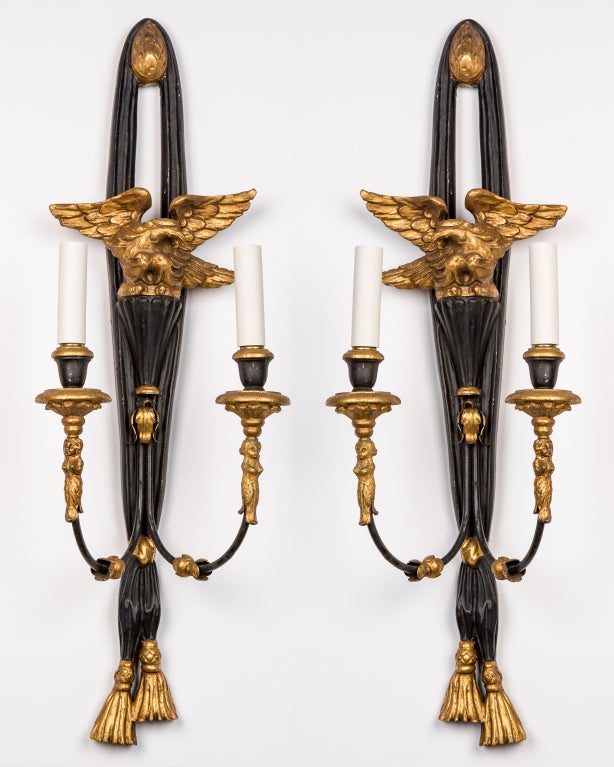 AIS2780
A pair of double light sconces in carved wood retaining their original painted and gilded finish. The backplates in the form of gathered drapery, the armbacks supporting a matched pair of eagles. Circa 1950s.

Dimensions:
Overall: 31-1/2