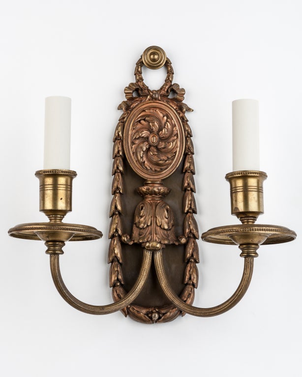 AIS2794
A pair of darkened brass double-light sconces with highly detailed bellflower-wreathed backplates. Signed by the New York maker E. F. Caldwell.

Overall: 11-1/2