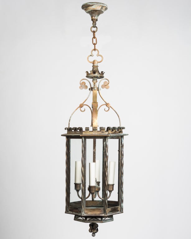 AHL3694
An octagonal lantern with crenelated, trefoil, and twist details, glazed with clear glass panels and lit with a four-branch cluster. Having its original aged bronze finish.

Minimum height: 52