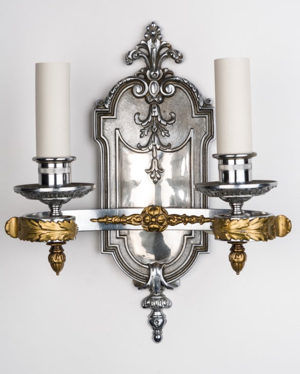 AIS2787

A pair of double light bronze sconces finished in chrome with polished bronze foliate details. The rectangular-section arms curve off the large backplates and scroll to a tight center to hold the candle cups and waxpans.

Overall: 15