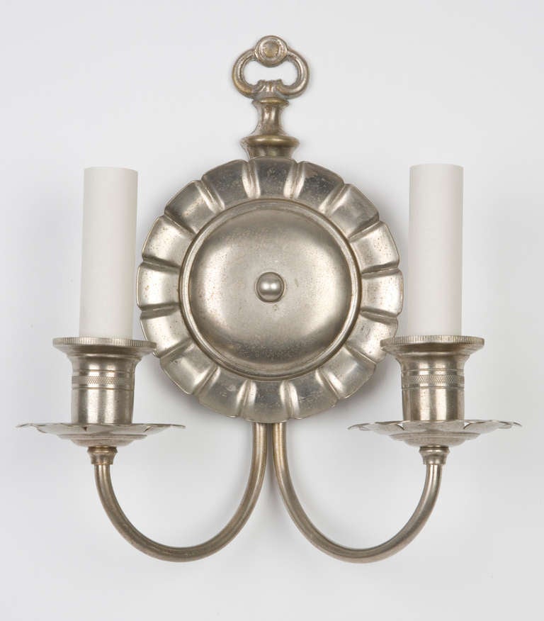 AIS2424

Circa 1920
A pair of double light sconces with pie-crust edged backplates in their original aged nickel finish.

Dimensions:
Overall: 11-1/4