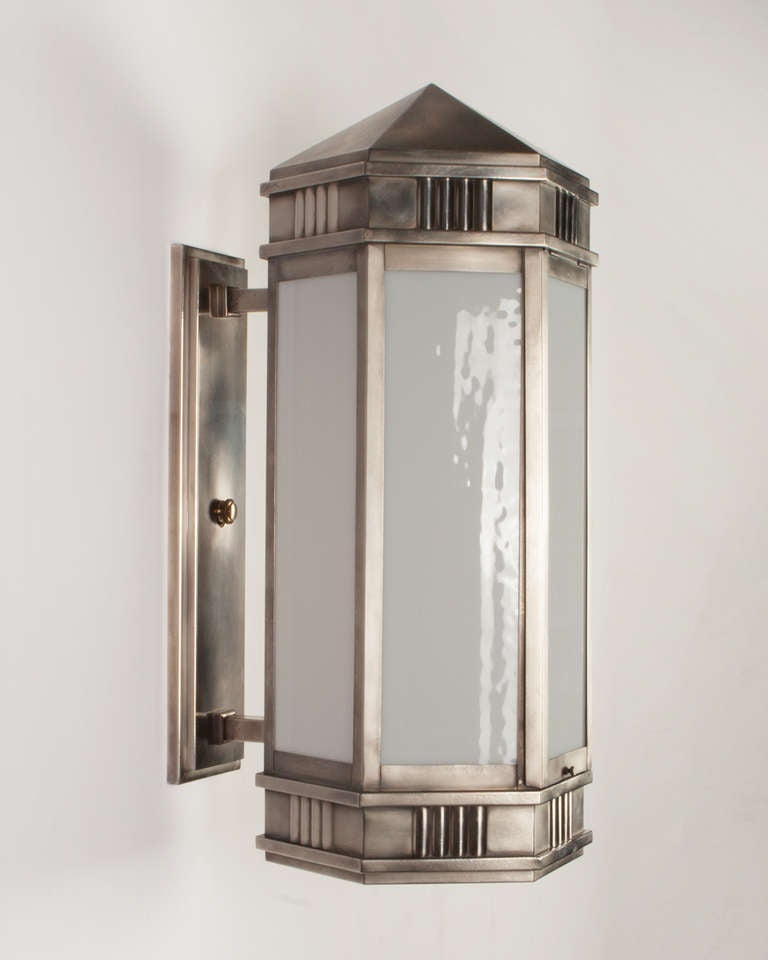 AEX0578

Circa 1930

A pair of antique wall lanterns in a weathered nickel finish. The hexagonal bodies are subtly detailed with reeds and topped with shallow peaked roofs. Glazed with textured opaline glass. From a Cleveland, Ohio office