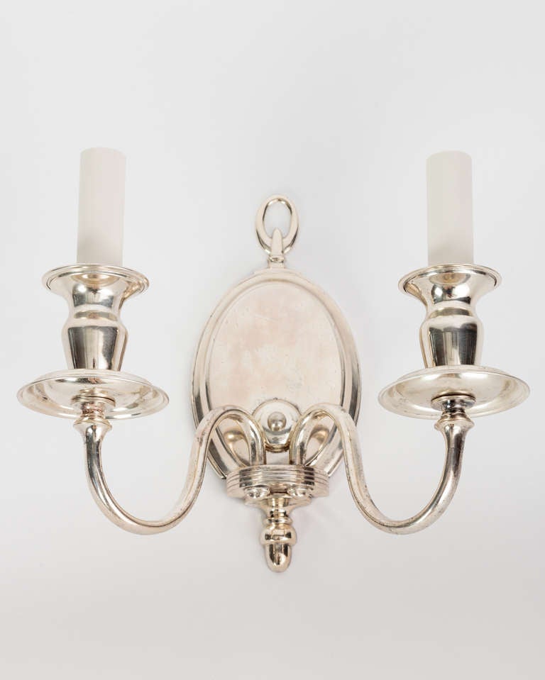 AIS2849

A two arm antique sconce having an oval backplate topped with a loop finial. The flared arms spring from an armback with incised linear details, supporting spun bobeches and cups. In a worn silverplate over bronze