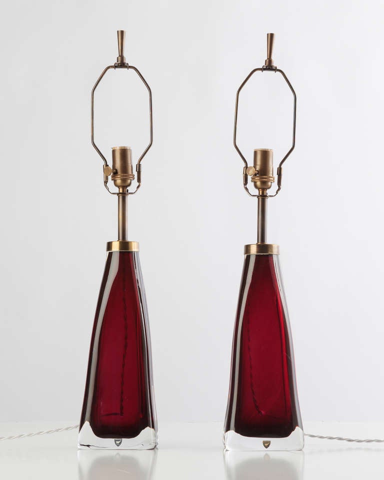 ATL1861

A pair of red glass table lamps with darkened brass fittings designed by Carl Fagerlund for the swedish glassmaker Orrefors. Due to the antique nature of this fixture, there may be some nicks or imperfections in the