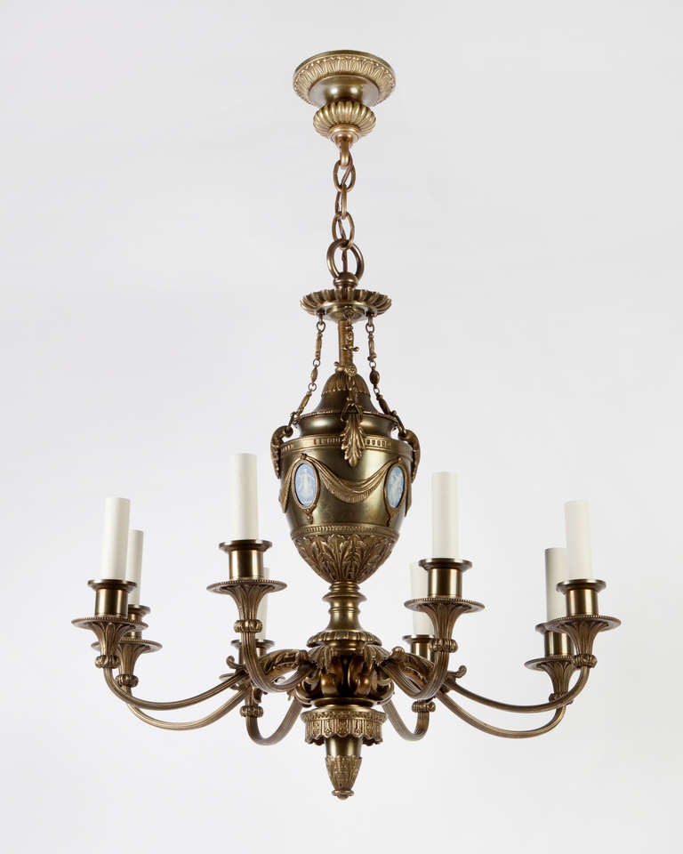 AHL3849
An antique eight-light chandelier having an urn-form body set with Wedgwood cameos. The reeded and foliate detailed scroll arms spring from a narrow point on the body to support delicate beaded wax pans and candle cups. Attributed to the