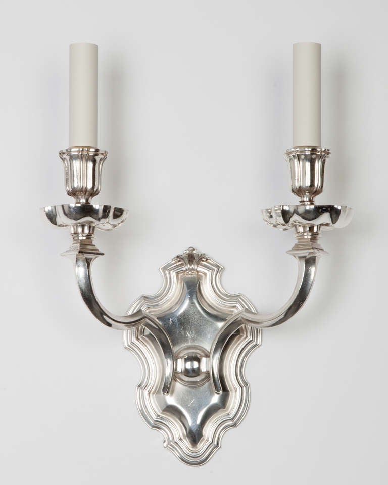 AIS2892
A pair of antique double light wall sconces having shield-form backplates and S-profile arms holding boldly figured wax pans and candle cups. Signed by the New York maker E. F. Caldwell. 

Dimensions

Overall: 16