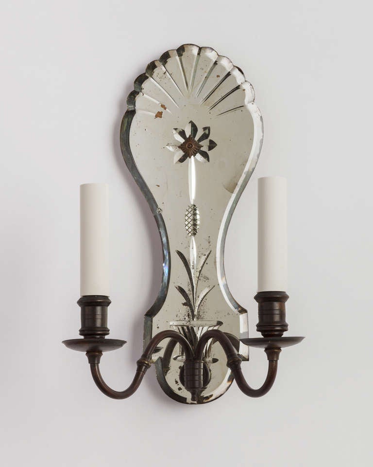 AIS2702

A pair of wheel-cut mirrorback sconces with fan-topped backplates. The metalwork in its original age-darkened brass finish. Due to the antique nature of these fixtures there are nicks and imperfections in the mirror as well as variations