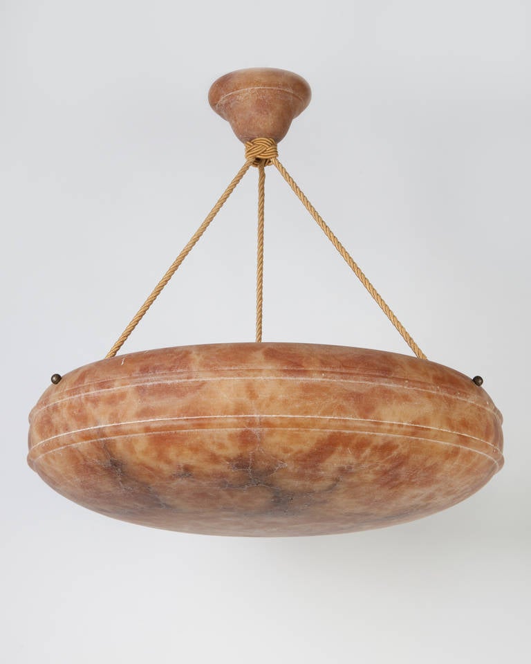 AHL3862.

A vintage inverted dome chandelier carved from veined burnt umber alabaster in a honed finish. The widest point is accented by a slim double bullnose. The dome is suspended with darkened brass rosettes and silk cords from a matching