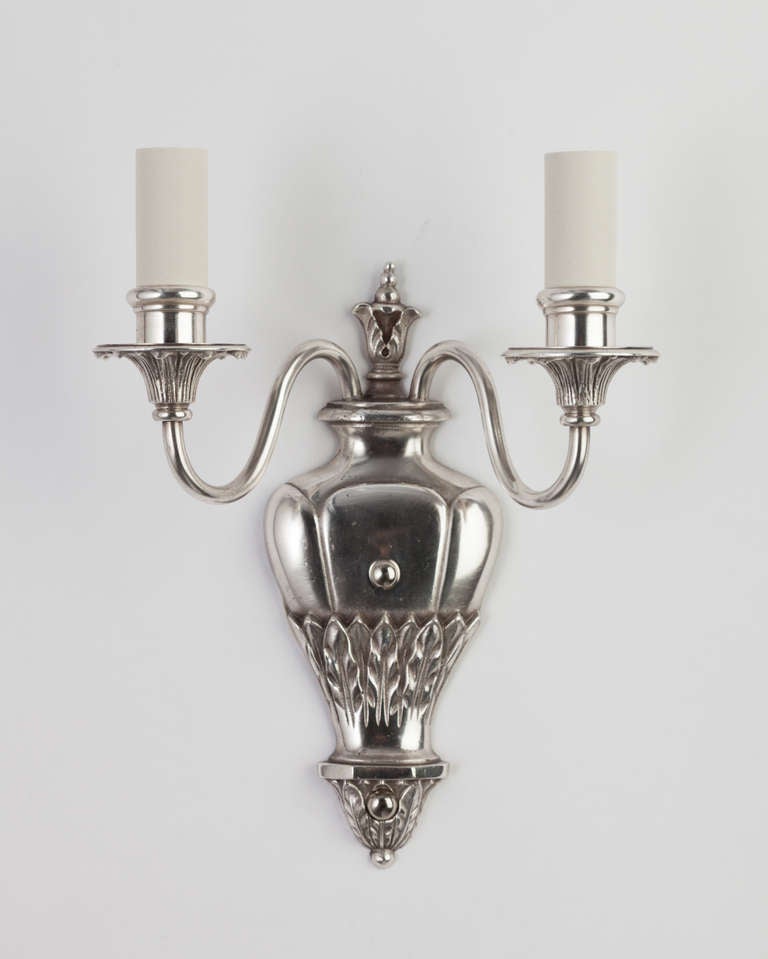 AIS2868
A pair of two arm sconces with bands of foliate details on the backplates and bobeches. In their original silverplate over cast bronze. Circa 1920s.

Dimensions:
Overall: 10-3/4