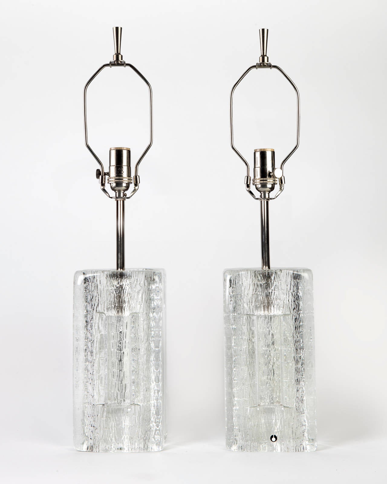 ATL:1896

A pair of textured cast glass lamps formed by two solid T-shapes connected in the middle. Having nickel fittings. Signed by the Swedish maker Pukeberg. Due to the antique nature of this fixture, there may be some nicks or imperfections