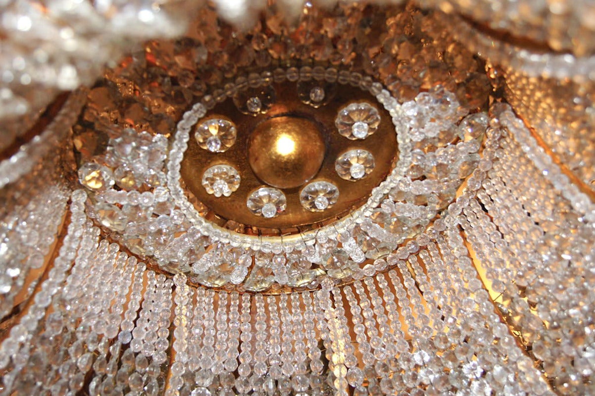 A large, French, gilt metal and crystals chandelier with 18 interior lights.
The gilt metal body with beaded crystal drops and with molded glass leaves and crystal flowers.
The interior lights are covered by woven crystals from the top.
   
