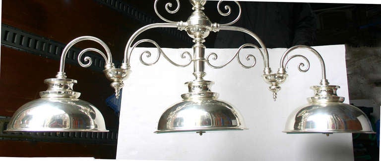 A circa 1950's English silver-plated billiard-style light fixture with three down shades, four candelabra lights in each (12 60w lights total).

Measurements:
Length: 72