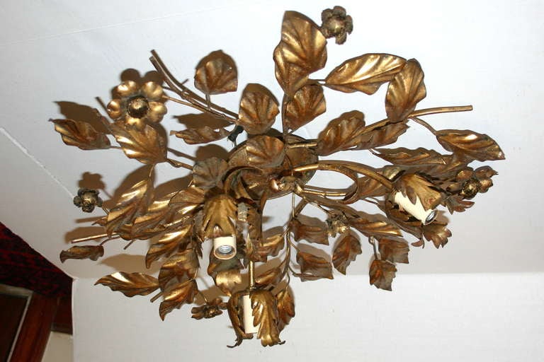 A circa 1930's French gilt metal flush mounted light fixture with 3 lights. The body has a foliage and floral motif.

Measurements:
Height (drop): 7.5