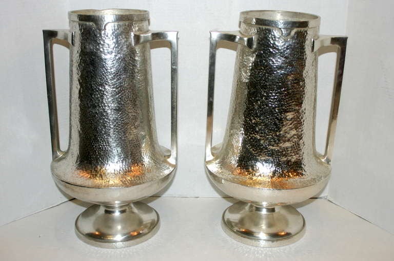 Paire de vases anglais en métal argenté des années 1920, avec corps et poignées texturés et martelés. Ils ont été laqués pour éviter le ternissement.

Mesures :
Hauteur : 18.5
