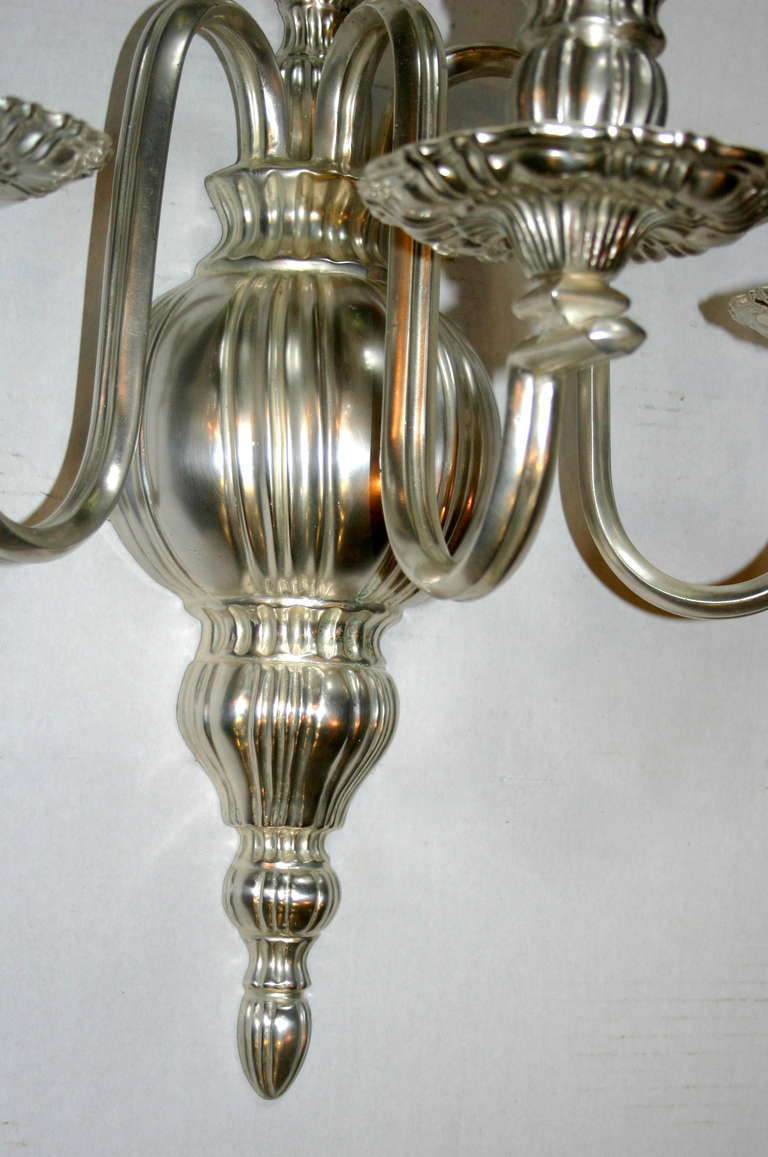 Pair of American neoclassic style large silver plated sconces with three lights. 

Height: 23.5 in.
Depth: 10.5 in.
Width/Length: 17.75 in.