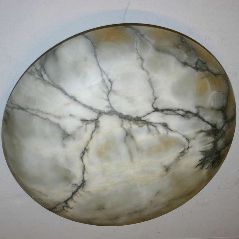 A carved alabaster fixture with warm white tone, charcoal color veins and interior lights. 

Measurements:
Diameter: 18