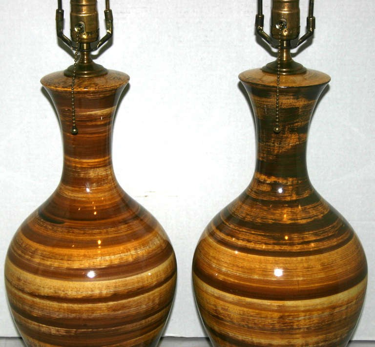 A pair of circa 1940s Italian moderne style porcelain lamps with bands of topes and brown colors. 
Lucite bases.