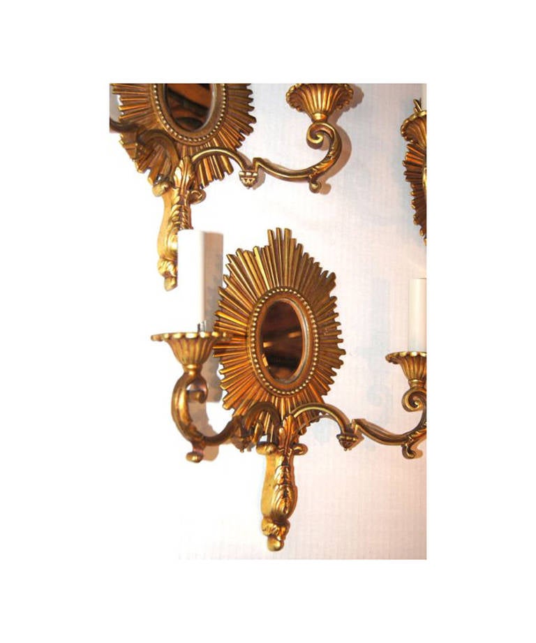 Set of four French, gilt bronze sunburst shaped sconces with mirror insets on backplate, double lights.

Measures: 14