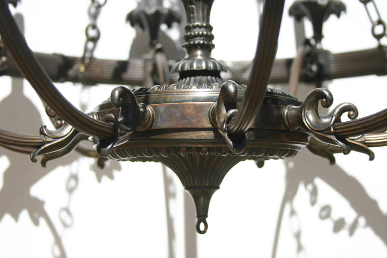 A pair of circa 1920s American neoclassic style patinated bronze chandeliers with ten-light each. Sold individually.

Measurements:
Drop 66