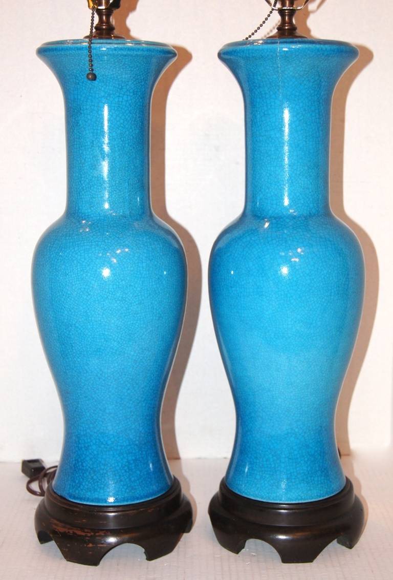 A pair of circa 1940’s French vase-shaped turquoise blue crackle-glazed porcelain table lamps with ebonized wood bases.

Measurements:
Height of body: 21.5”
Height to shade rest 35″
Diameter at widest: 7″
