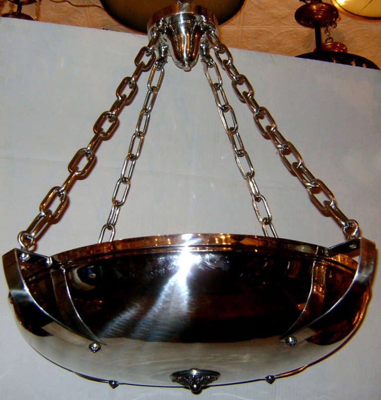 An English neoclassic-style silver plated light fixture supported by 4 chains with interior lights.

Measurements:
Diameter: 28