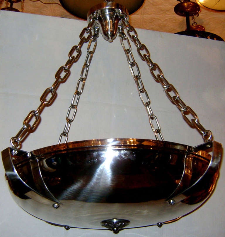 Un lampadario inglese in stile neoclassico placcato argento sostenuto da 4 catene con luci interne.

Misure:
Diametro: 28