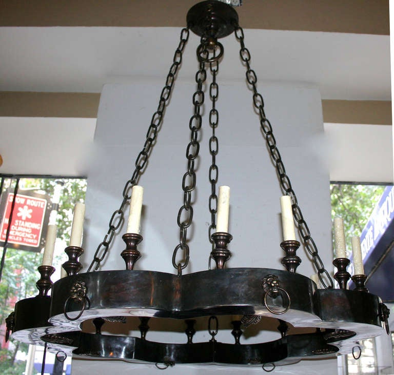 A pair of English, 1940s patinated bronze chandeliers with lion's heads details and 16 lights.