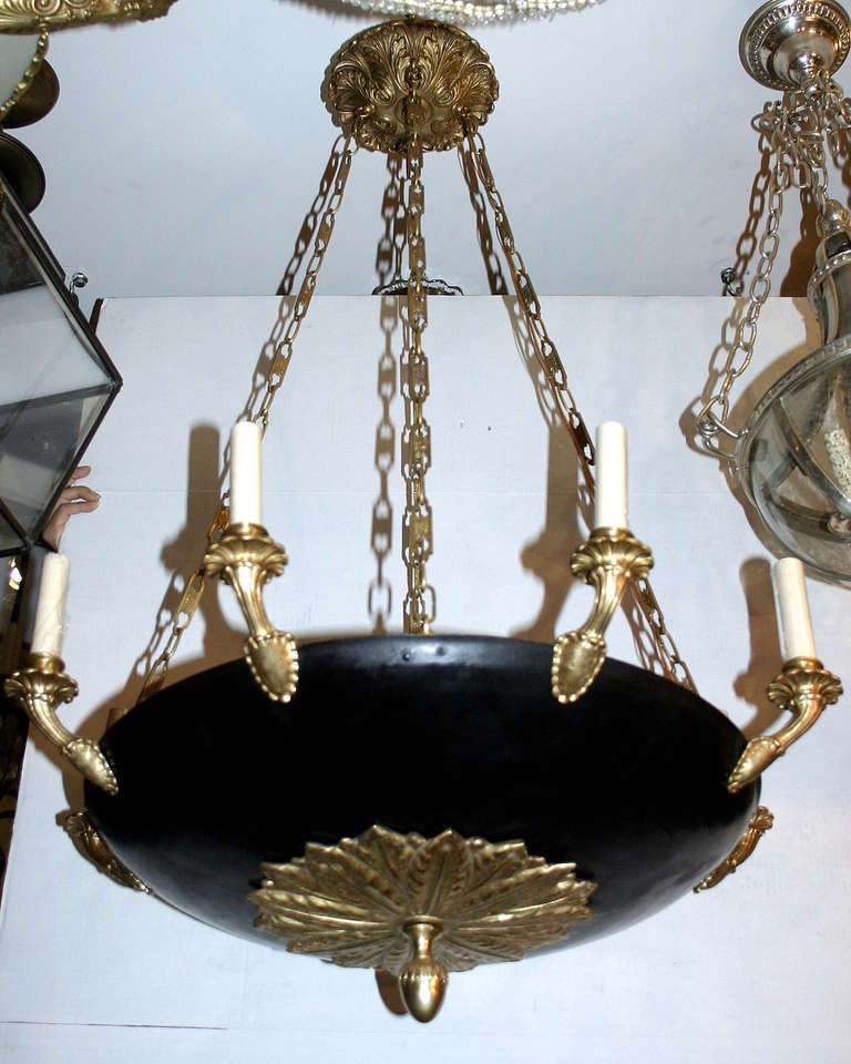 Pair of large bronze and tole, circa 1940s French Empire style chandeliers with eight lights. With foliage detail bottom inset.
The black tole body is covered at the top by a tole inset, so the interior is not seen from above.